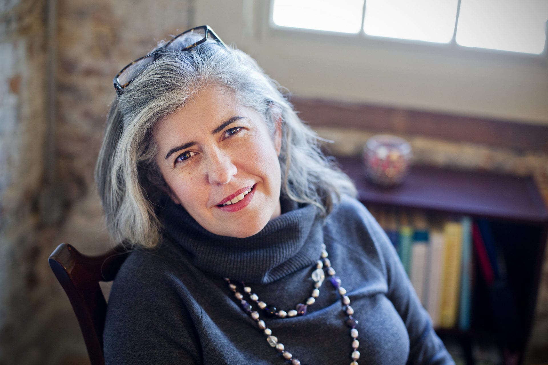 A woman with grey hair wearing glasses and a necklace.